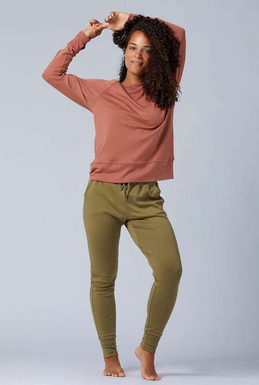 Woman wearing loungewear crewneck sweatshirt made from sustainable TENCEL and organic cotton in copper brown and olive green lounge pants